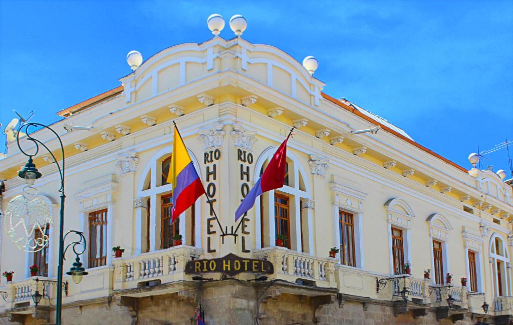 un edificio con dos banderas delante en Rio Hotel, en Riobamba
