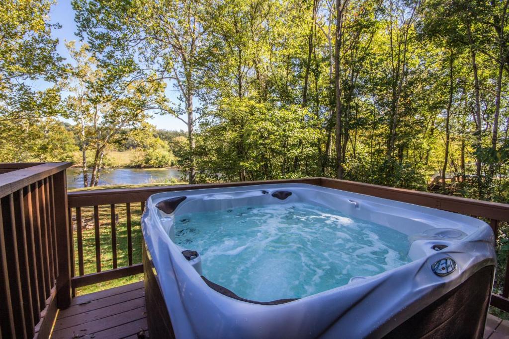 a hot tub on a deck with a view of a river at Fish Trap cabin on the Shenandoah River in Oak Hill
