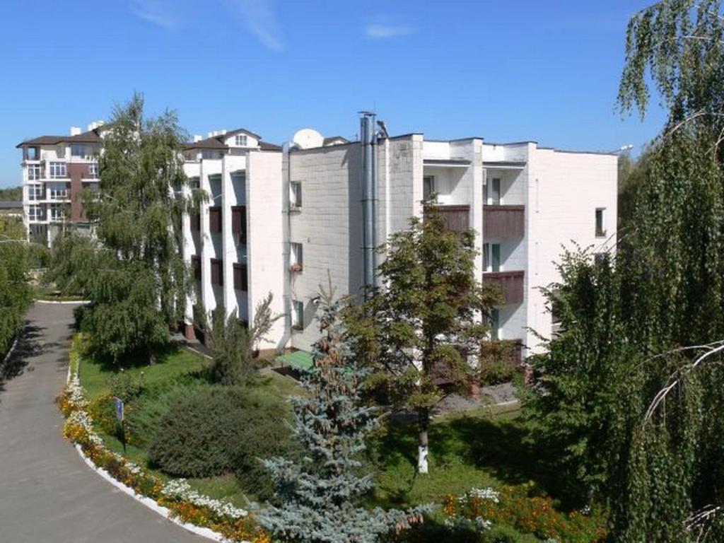 ein großes weißes Gebäude mit Bäumen davor in der Unterkunft Hotel Complex Vizit in Kozin