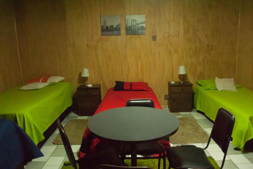 a room with two beds and a table and chairs at Hostel 1760 in Talca