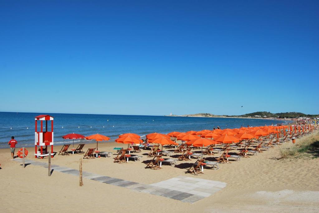 una playa con sillas y sombrillas naranjas y el océano en Santa Maria villaggio turistico, en Vieste