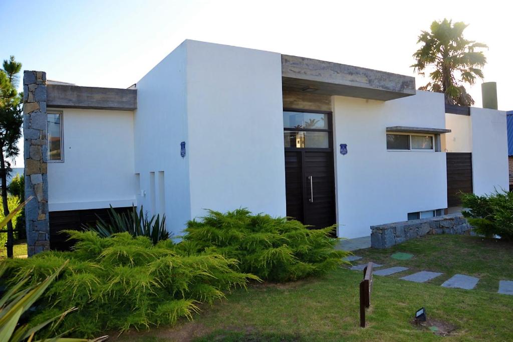una casa blanca con una puerta negra en Best Vila in Manantiales - El Chorro, en Manantiales