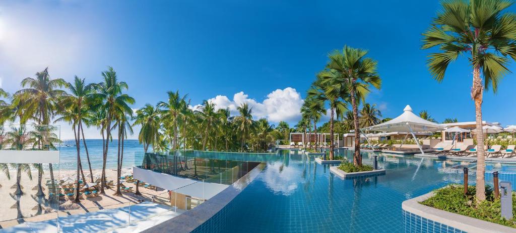 a resort swimming pool with palm trees and the ocean at Henann Crystal Sands Resort in Boracay