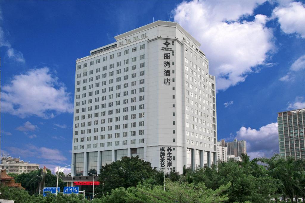 un edificio alto y blanco con árboles delante en Shenzhen Longgang Rivan Hotel, en Longgang