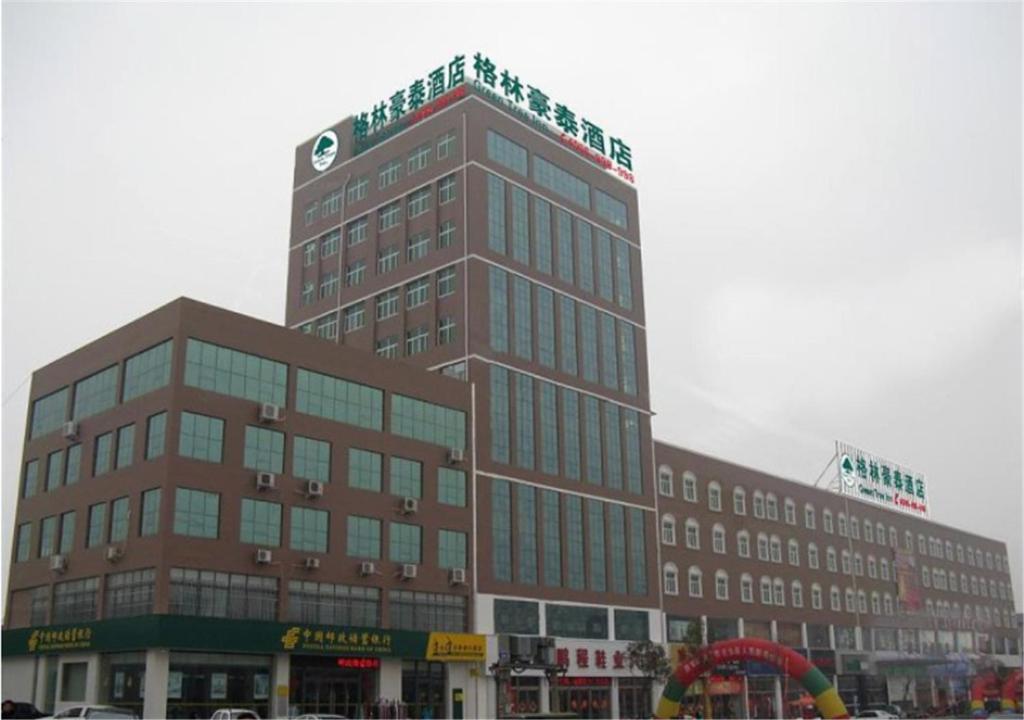 a tall building with a sign on the top of it at GreenTree Inn Jining Wenshang Baoxiang Temple Express Hotel in Wenshang