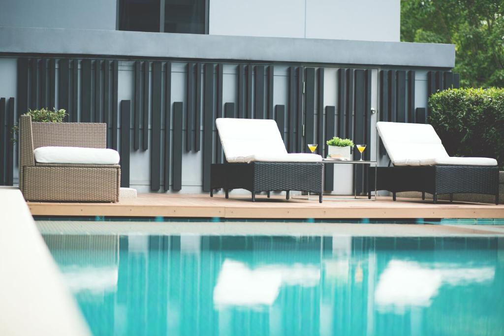 a group of chairs sitting next to a swimming pool at Park 19 Hotel in Bangkok