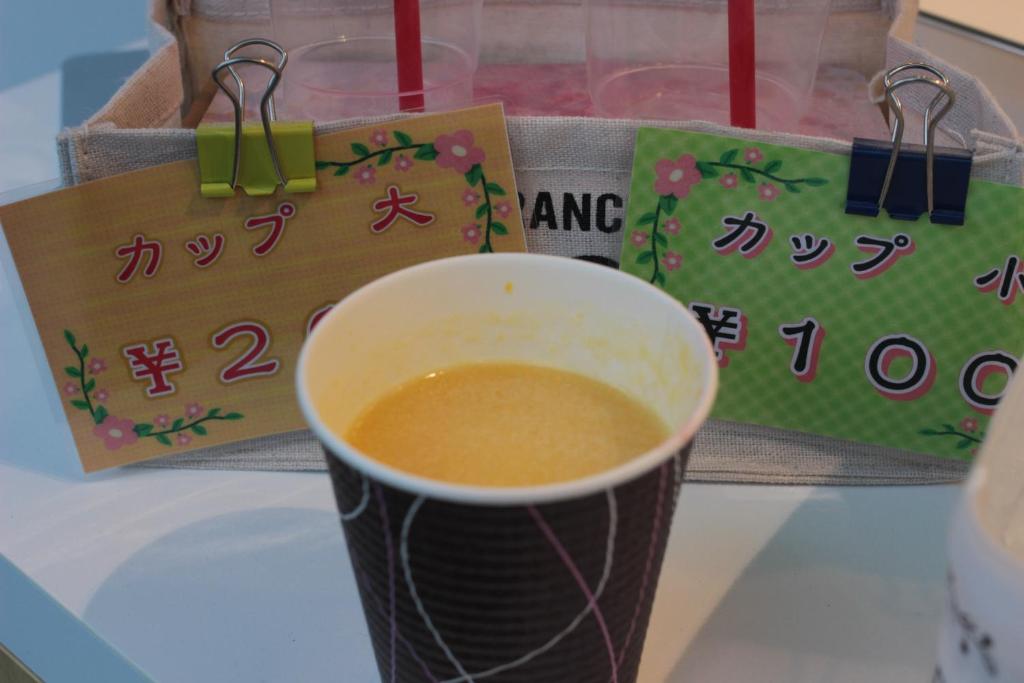 a cup of coffee sitting on a table with signs at Guesthouse COCO Hiroshima (Female Only) in Hiroshima