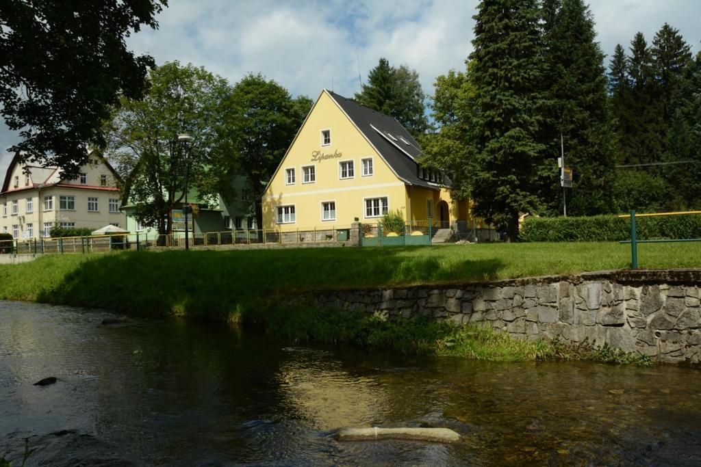 a yellow house sitting next to a river at Lipanka in Lipova Lazne