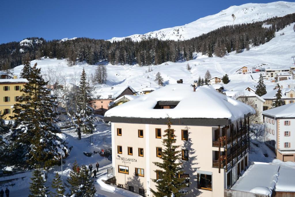 un bâtiment dans la neige avec une montagne en arrière-plan dans l'établissement Hotel Bellavista Ftan, à Ftan