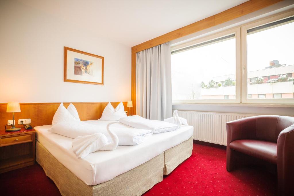 a bedroom with a bed with white pillows and a chair at Am Neutor Hotel Salzburg Zentrum in Salzburg