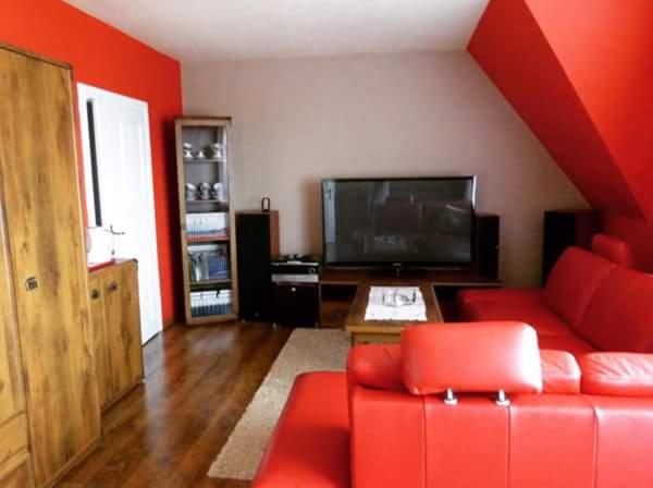 a living room with a red couch and a flat screen tv at Noclegi Barbara in Czorsztyn