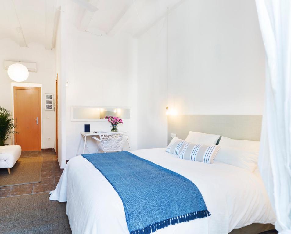- une chambre avec un grand lit blanc et une couverture bleue dans l'établissement Victoria Site-Mercat Central, à Valence