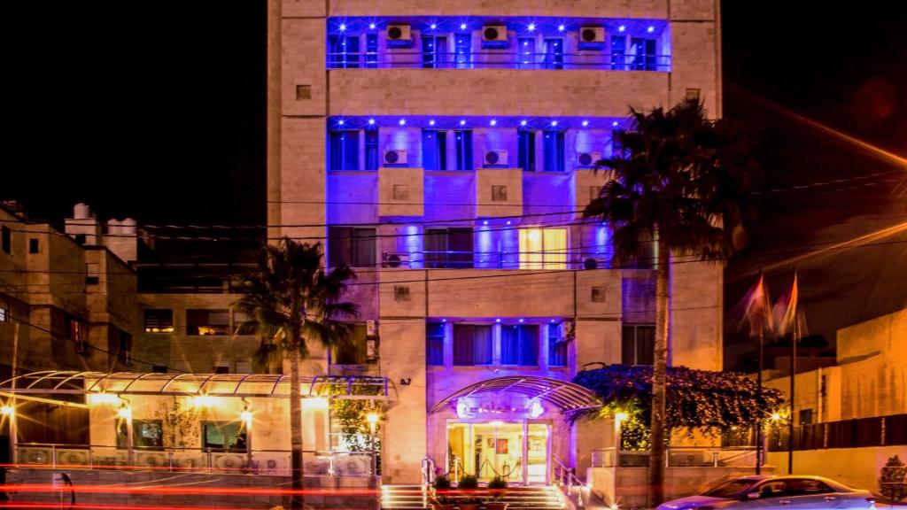 un bâtiment avec des lumières bleues allumées la nuit dans l'établissement Aghadeer Hotel, à Amman