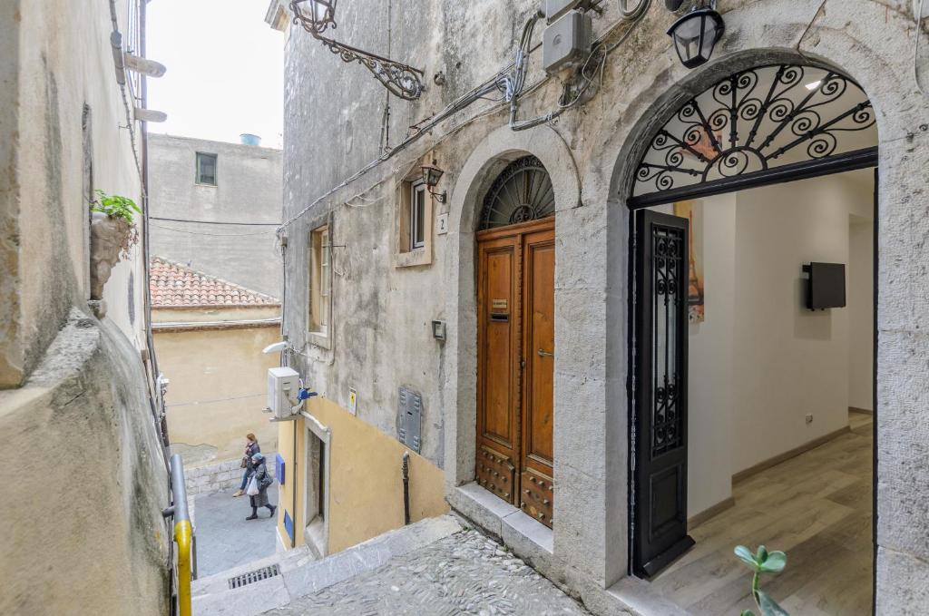 een steegje in een oud gebouw met een houten deur bij Dreaming Taormina Apartment in Taormina