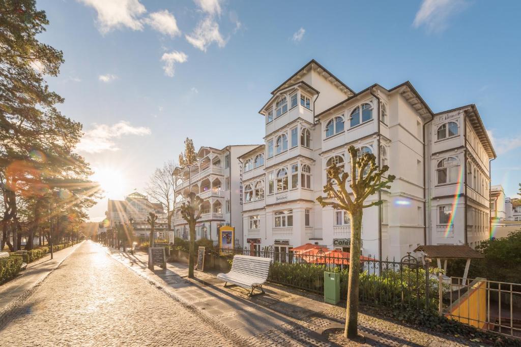 um edifício numa rua com um banco à frente em Hotel Villa Belvedere em Binz