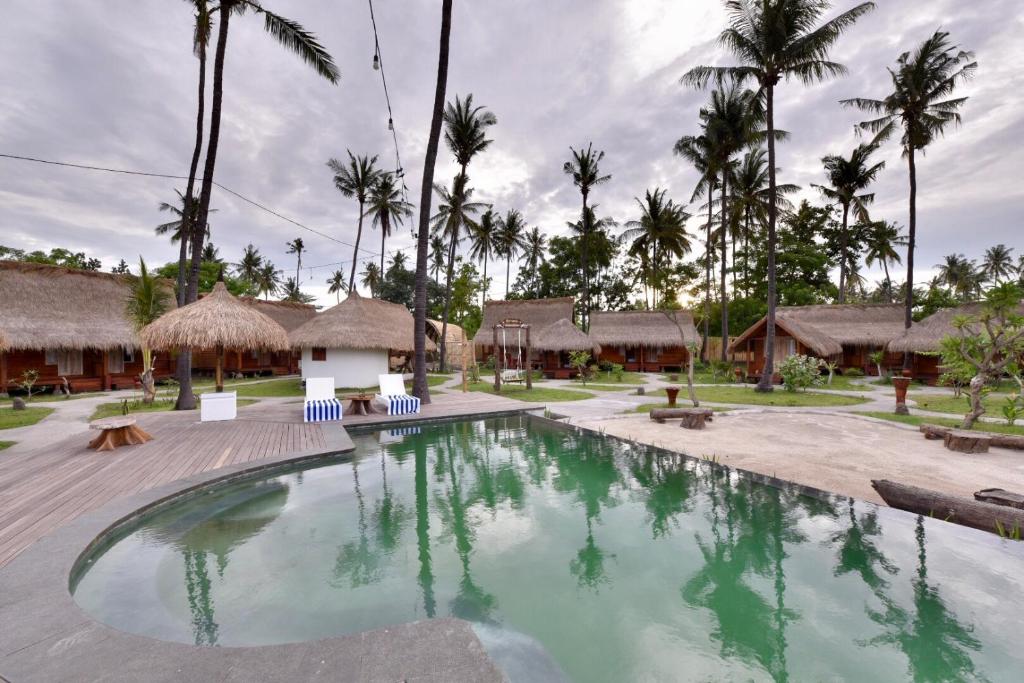a swimming pool at a resort with palm trees at Beranda Ecolodge in Gili Islands