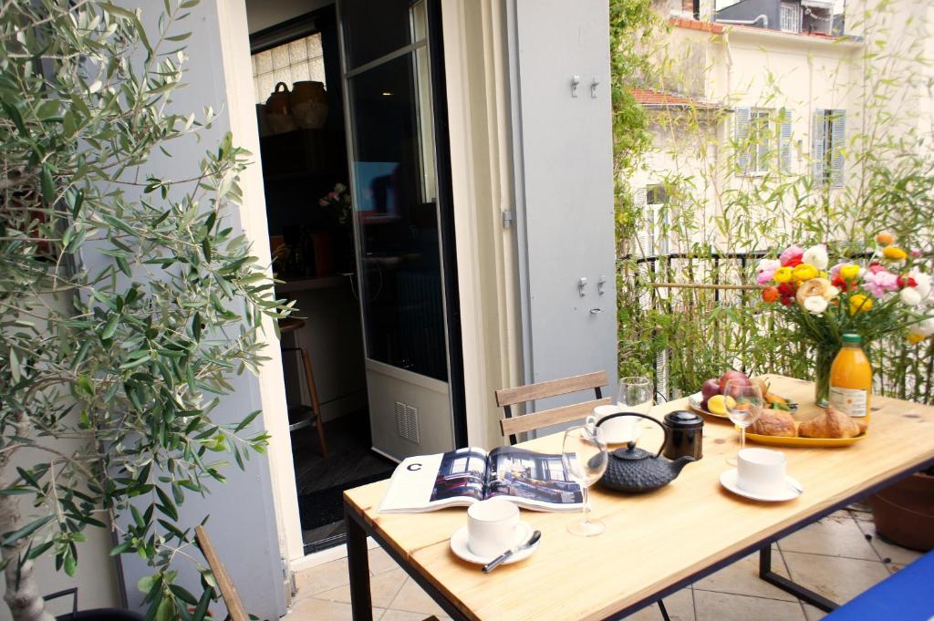 una mesa de madera en un patio con flores en Ze Perfect Place - Élégant appartement avec terrasse - Promenade des Arts en Niza