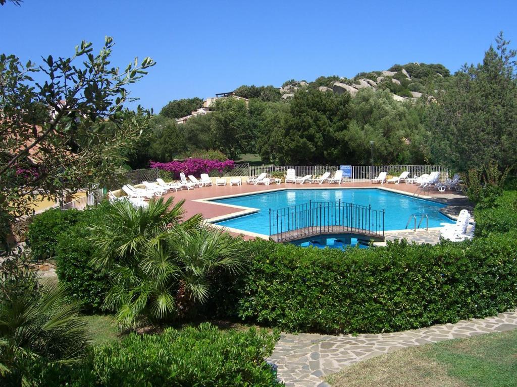 a large swimming pool with chairs and trees at Rotondo Residence - Simar Vacanze in Porto Rotondo