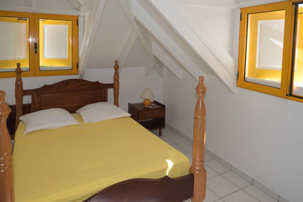 1 dormitorio con 1 cama con colcha amarilla en Maison Duplex "Josué" vue sur Marina, en Grand-Bourg