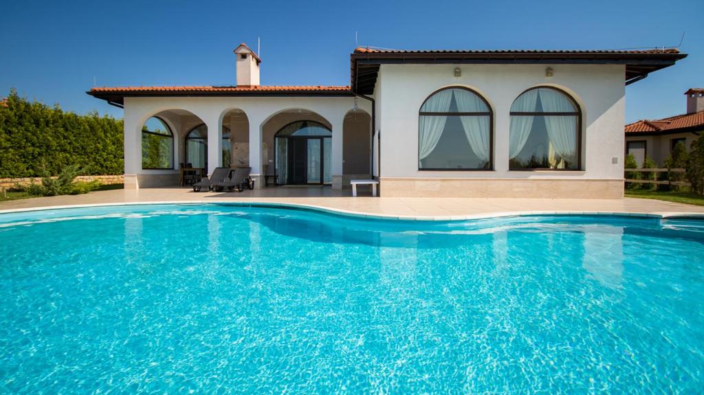 a villa with a swimming pool in front of a house at Private Villa First line with sea view in BlackSeaRama Golf A PLUS LOCATION PRIVACY POOL in Balchik