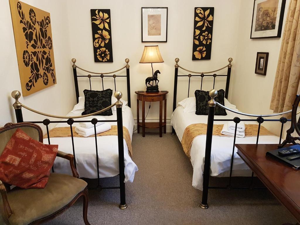 a bedroom with two beds and a chair and a desk at Gothic House in East Grinstead