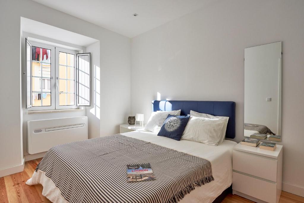een witte slaapkamer met een bed en een raam bij Apartment Guarda-Mor in Lissabon