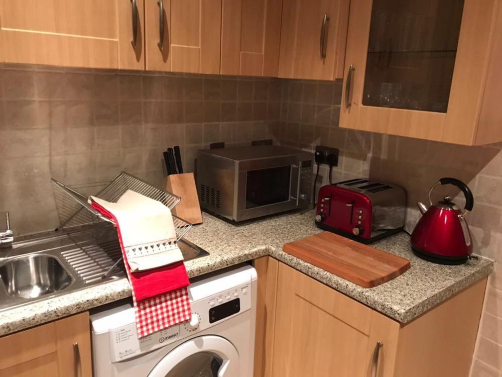 a kitchen with a microwave and a washing machine at Finchley Apartment in London