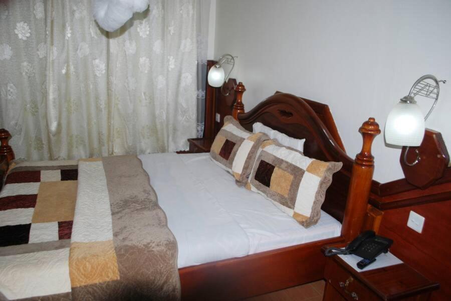 una camera con letto in legno e cuscini sopra di Palm world Hotels Mbarara a Mbarara