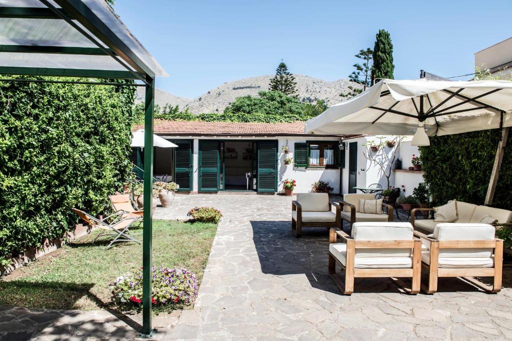 patio z krzesłami, parasolem i domem w obiekcie Ciuri Ciuri Mondello w mieście Mondello