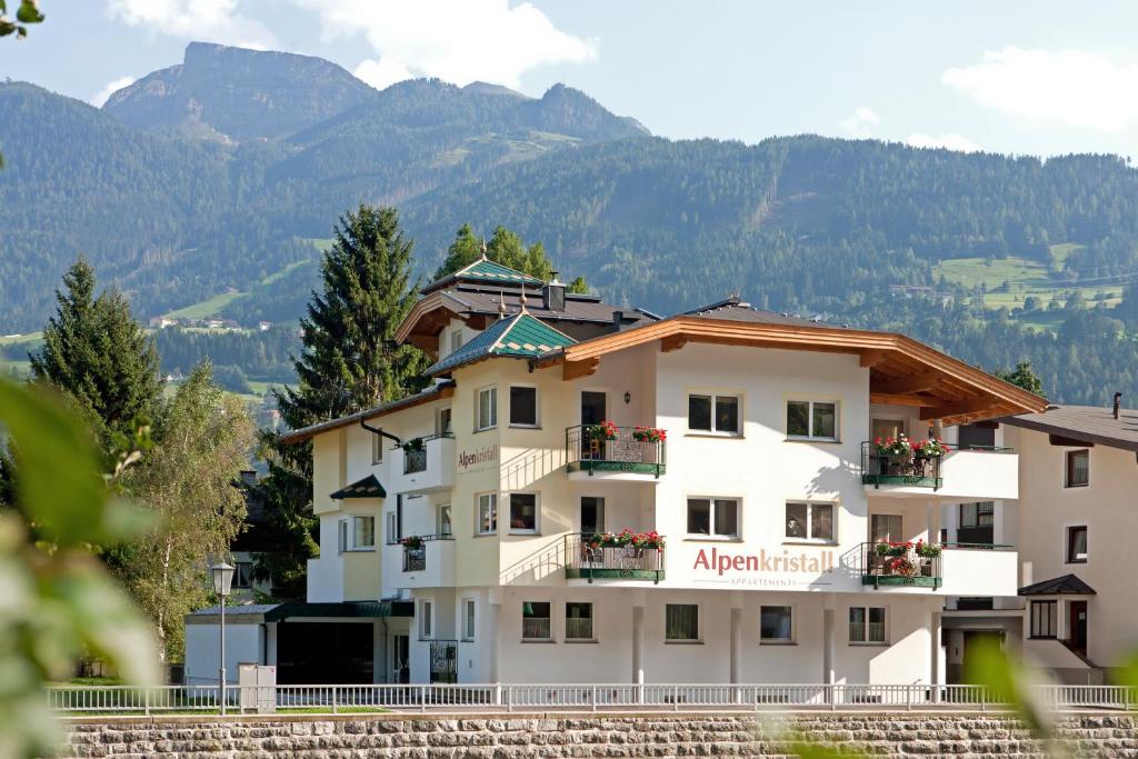 ein großes weißes Gebäude mit Bergen im Hintergrund in der Unterkunft Appartements Alpenkristall in Zell am Ziller