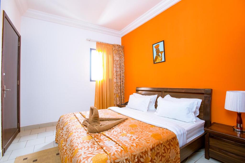 1 dormitorio con 1 cama con pared de color naranja en Le Feto, en Dakar