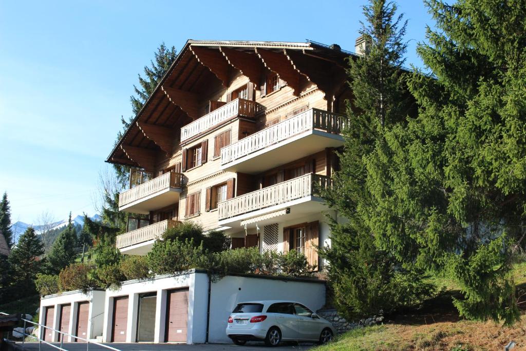 un edificio con un'auto parcheggiata di fronte di Appartement Le Roc a Gstaad