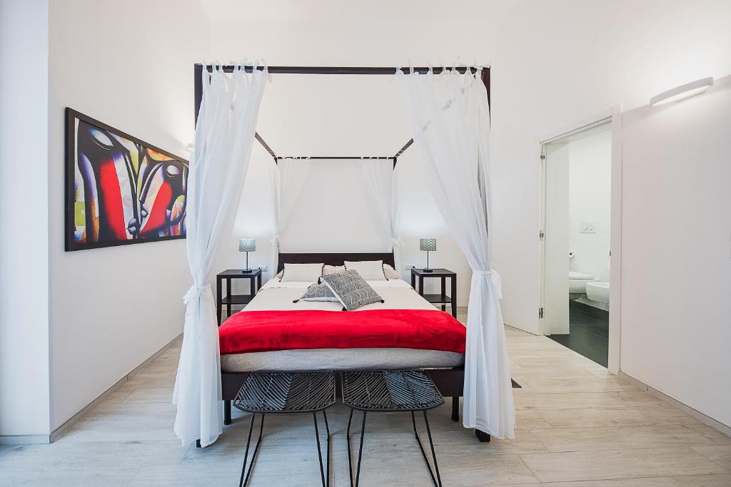 a bedroom with a canopy bed with a red blanket at La casa di Giovanni in Lecce