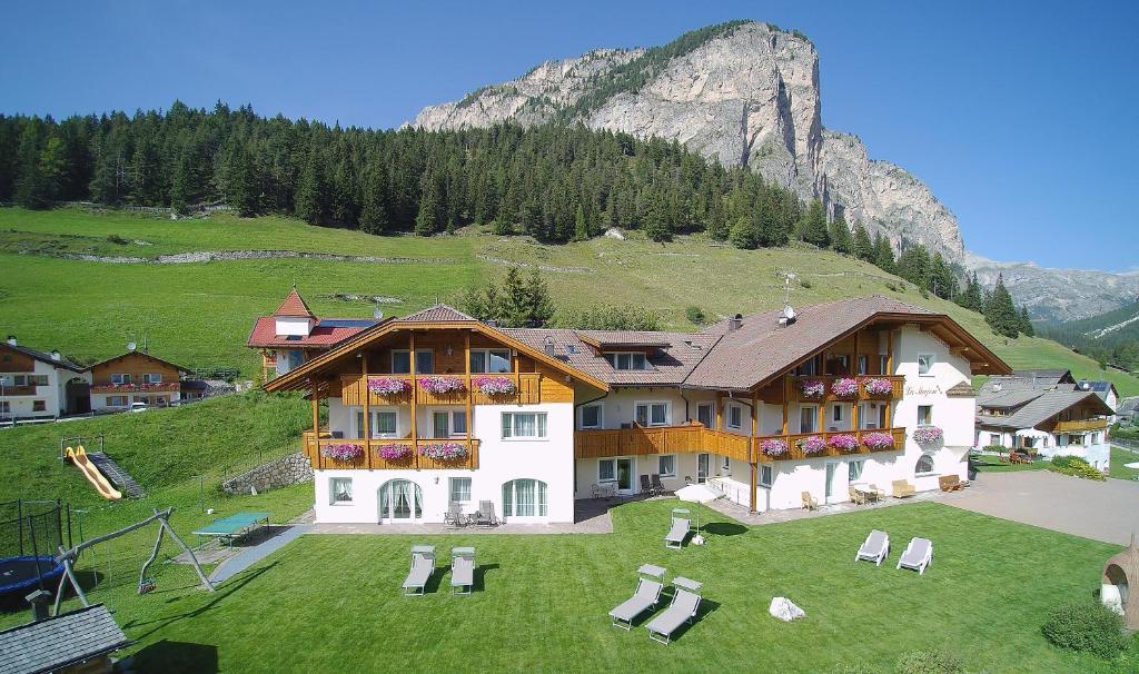 a house on a hill with a mountain in the background at Garni La Majon in Selva di Val Gardena