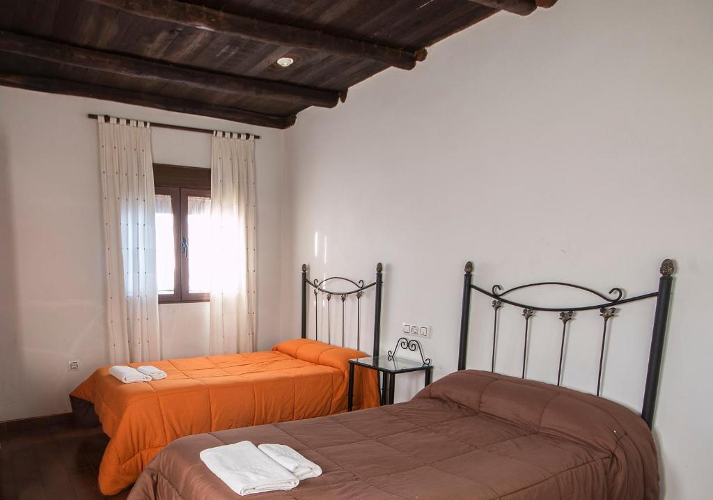 1 dormitorio con 2 camas con sábanas de color naranja en El Tirol, en Cantagallo
