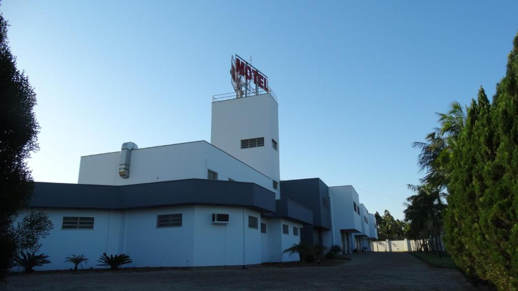 ein weißes Gebäude mit einer Flagge darüber in der Unterkunft Xenon Motel (Adult Only) in Criciúma