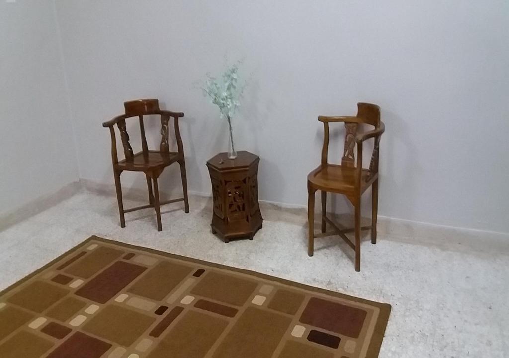 Zimmer mit 2 Stühlen und einem Tisch mit Vase in der Unterkunft Batu Berendam Homestay in Malakka