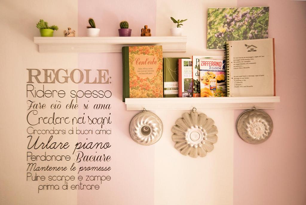 a shelf with books and a sign on a wall at La Casa di Ortensia in Parma