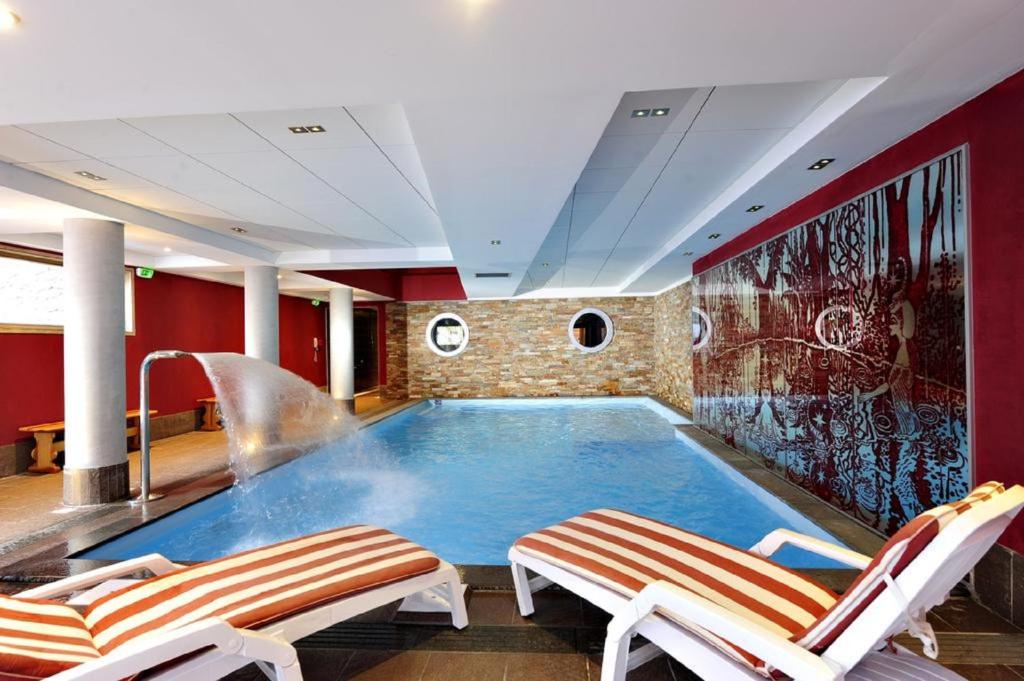 ein großer Pool in einem Zimmer mit zwei Stühlen in der Unterkunft T2 RESIDENCE ANTARES 4* pieds des pistes in Risoul
