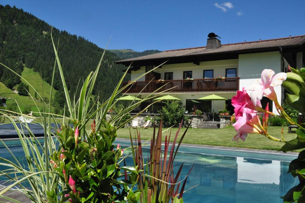 - une vue sur une maison avec une piscine et des fleurs dans l'établissement Hotel LÄRCHENHOF, à Kleinarl