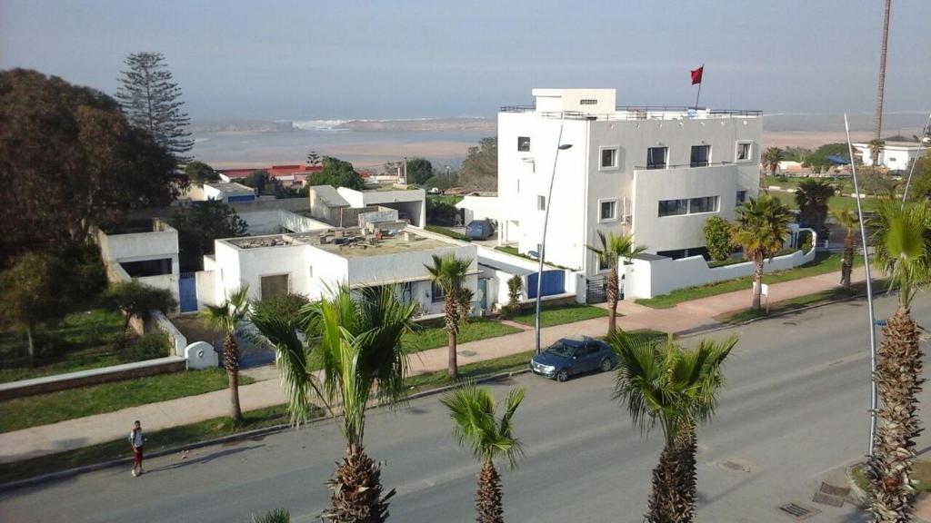 un bâtiment blanc avec des palmiers en face d'une rue dans l'établissement Thalassa, à Oualidia