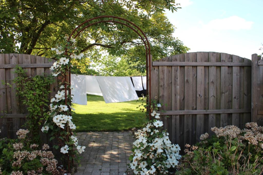 una valla de madera con un arco de flores blancas en Safine B&B en Fåborg