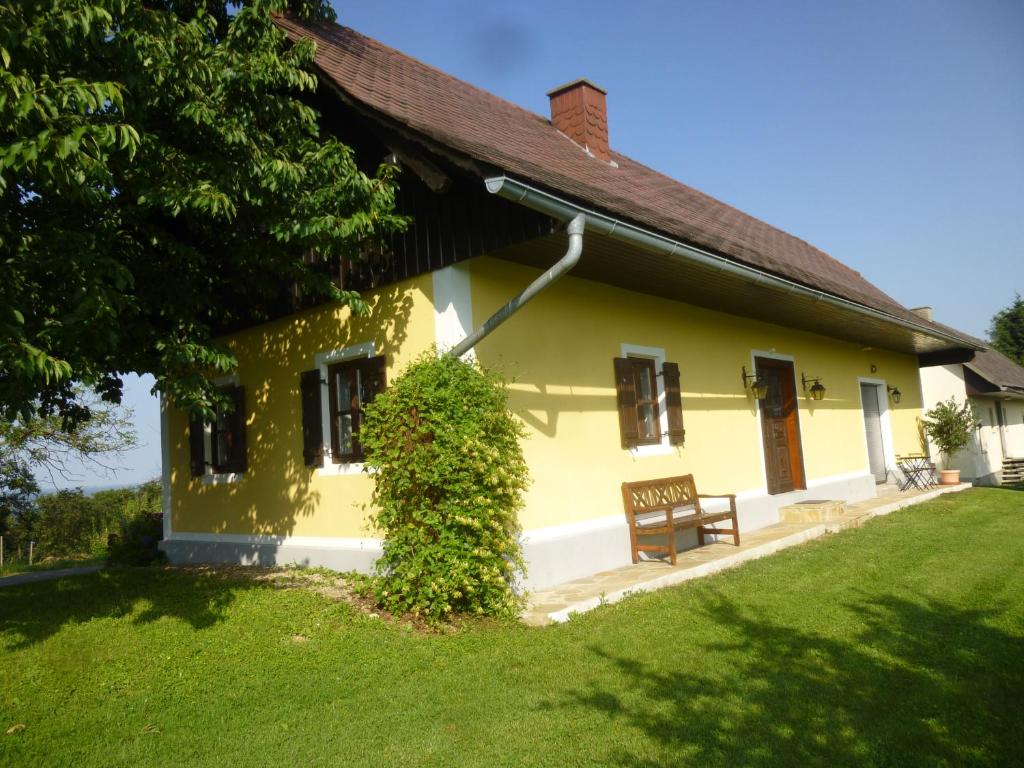 una casa amarilla con un banco en el patio en Ferienhaus Gründl, en Leibnitz