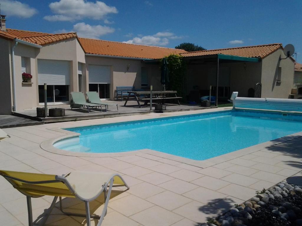 a swimming pool with a table and chairs next to a house at La Chambre des Amis in Parthenay