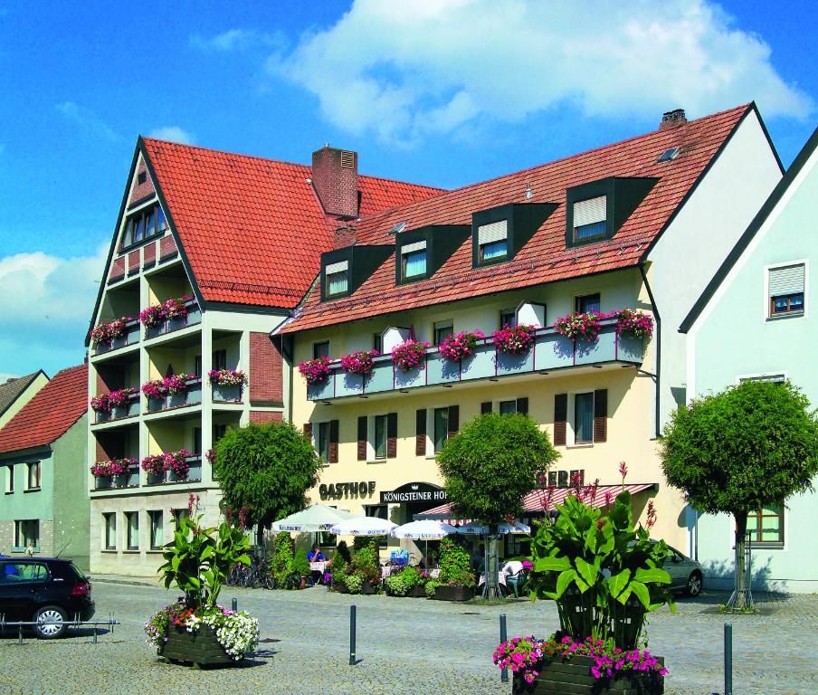 a large building with a red roof and flowers at Königsteiner Hof in Königstein in der Oberpfalz