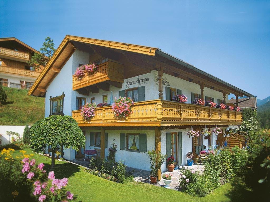 a large building with a balcony with flowers on it at Ferienwohnung Bergfrieden in Krün