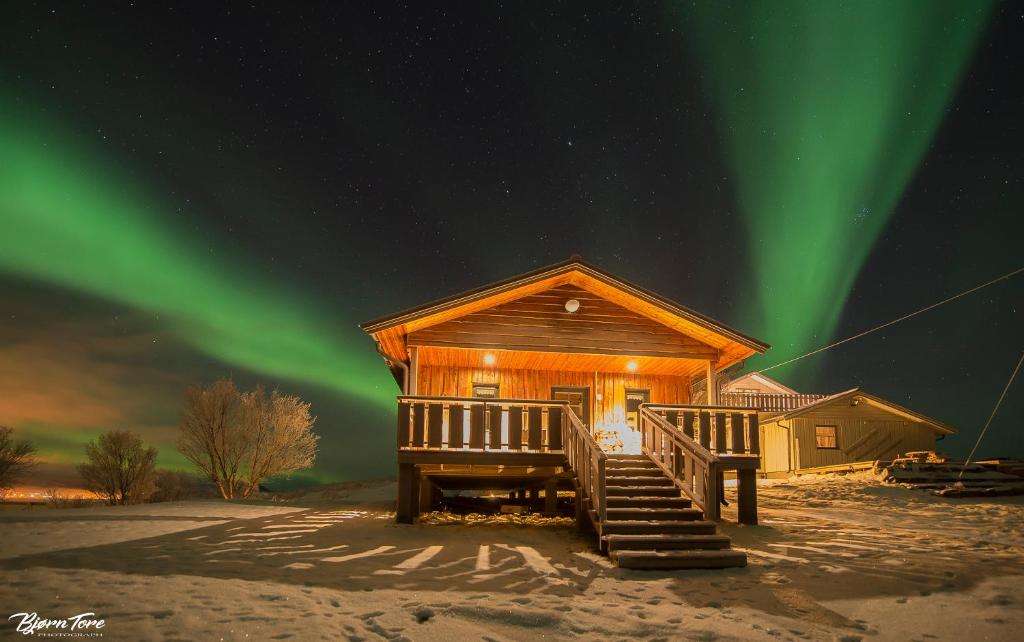 a log cabin with the northern lights in the sky at Bringnes Camp in Russenes