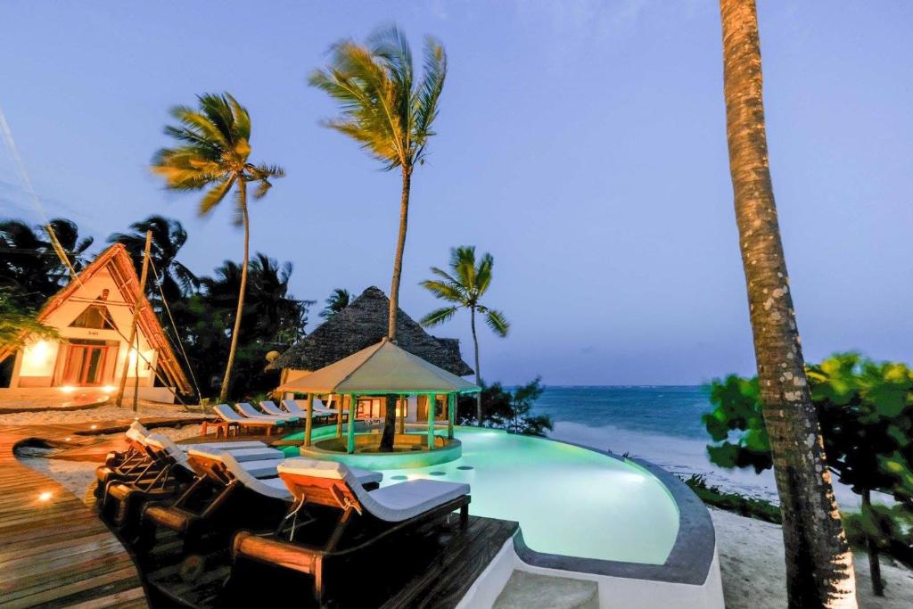 a resort with a pool and chairs and palm trees at Baladin Zanzibar Beach Hotel in Michamvi