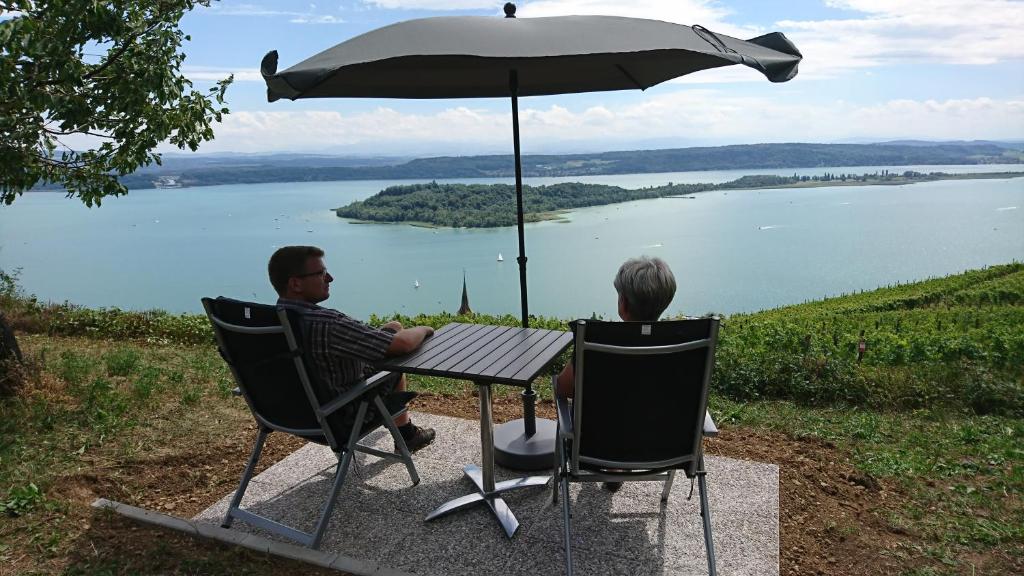 duas pessoas sentadas numa mesa debaixo de um guarda-chuva em Ferien auf dem Weingut em Ligerz