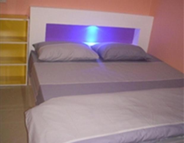 ein Schlafzimmer mit einem Bett mit lila Kopfteil in der Unterkunft Baan Kaneang in Ko Larn